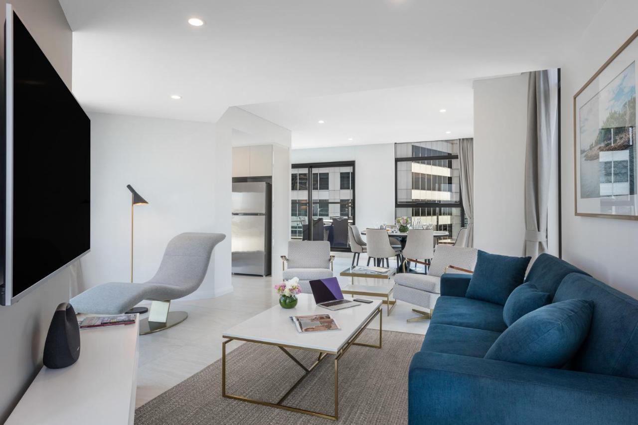 فندق أجنحة ميريتون سوسيكس ستريت سيدني المظهر الخارجي الصورة The photo shows a modern living space that features a bright and stylish interior. Key elements include:

- A sleek blue sofa and a light gray lounge chair, providing comfortable seating.
- A coffee table with a minimalist design, positioned in front